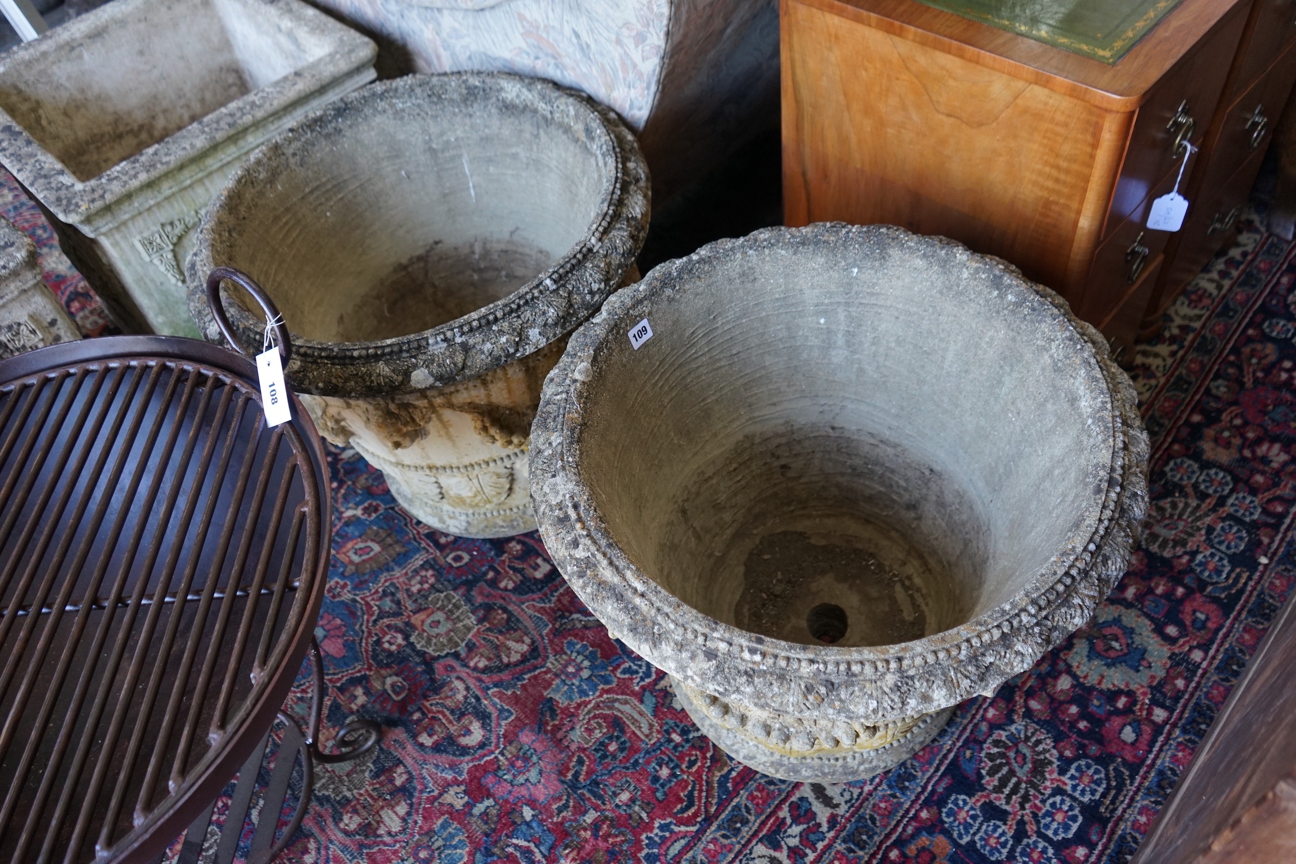 A pair of circular reconstituted stone garden planters with fruit swagged mask bodies, diameter 59cm, height 50cm